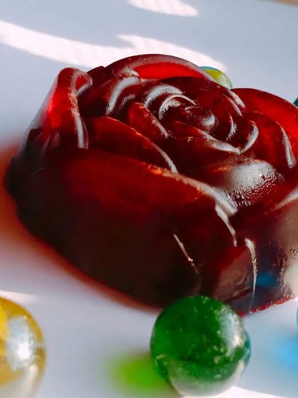 A beautifully crafted Red Wine soap in the shape of a rose, surrounded by decorative marbles. It's a piece of art that's also great for your skin.
