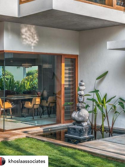 A tranquil water body with a stone sculpture, situated next to a glass-walled dining room. The placement ensures that the calming presence of water and art is a part of the daily dining experience.