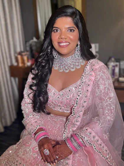 A stunning reception look in a pink lehenga. The makeup is glamorous and sophisticated, with a focus on her beautiful diamond jewelry.