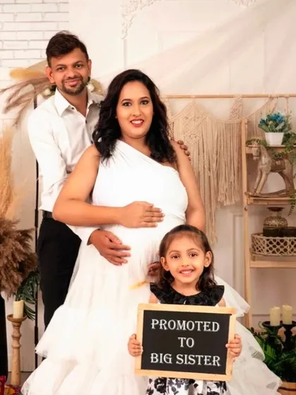 A beautiful family portrait announcing a new arrival, with the big-sister-to-be holding a chalkboard sign.