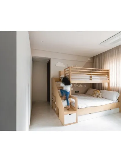 A child joyfully climbs the bunk bed stairs, which feature open cubbies for toys and books.