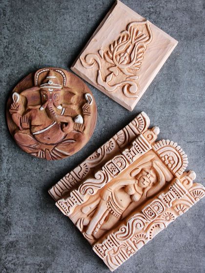 A collection of finished relief tiles, featuring intricate designs of Ganesha, a Salabhanjika, and a lotus flower.