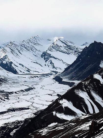 Moody, dramatic peaks in the Himalayas, with layers of mountains fading into the distance.