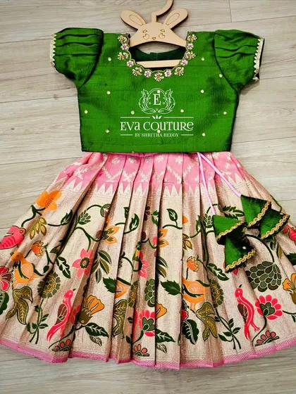 A lovely Kalamkari lehenga with a bird and flower motif. The green blouse has delicate embroidery, and the set is finished with cute bow-shaped tassels.