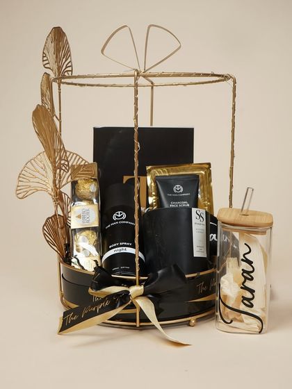 A sophisticated black and gold themed birthday hamper for him. This gift includes men's grooming products, a personalized glass, a scented candle, and Ferrero Rocher chocolates.