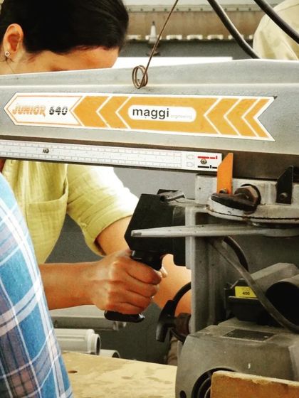 A close-up of a student operating the radial arm saw, focusing on the hand position and control required for safe and accurate operation.