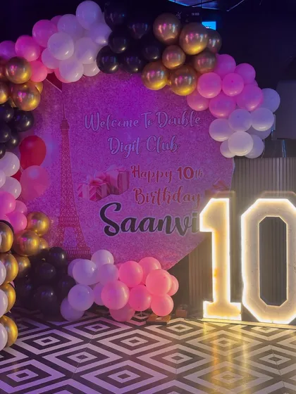 I also plan stylish parties for older kids and teens, like this 'Double Digit Club' 10th birthday. The setup includes a custom printed ring backdrop, a chic balloon arch in pink, black, and gold, and a large light up marquee number.