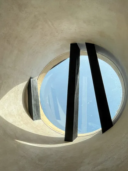 A skylight at the House of Galleries is framed by the geometry of charred wooden rafters. This detail not only illuminates the space but also brings a touch of nature indoors through its form and materiality.