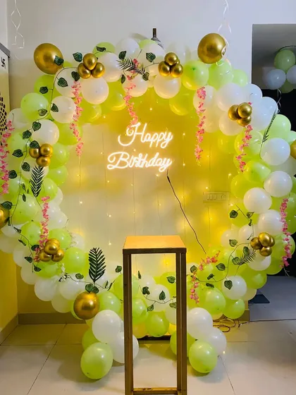A fresh and vibrant birthday setup with a circular balloon arch in lime green and white. I added some gold balloon accents and pink floral vines for a touch of elegance, with a cake stand in the middle.
