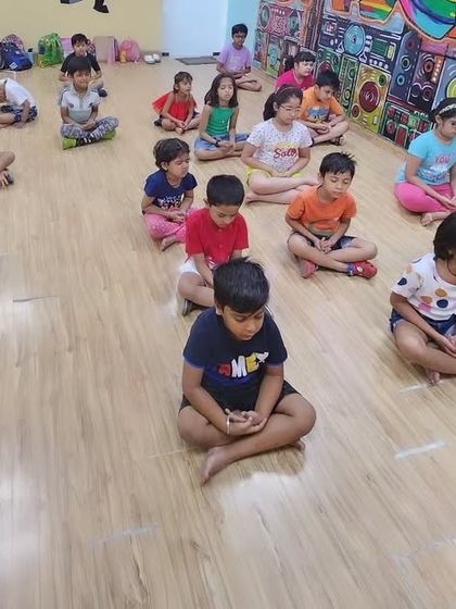 A moment of calm and focus. The kids are practicing a simple meditative pose, learning to quiet their minds and connect with their breath.