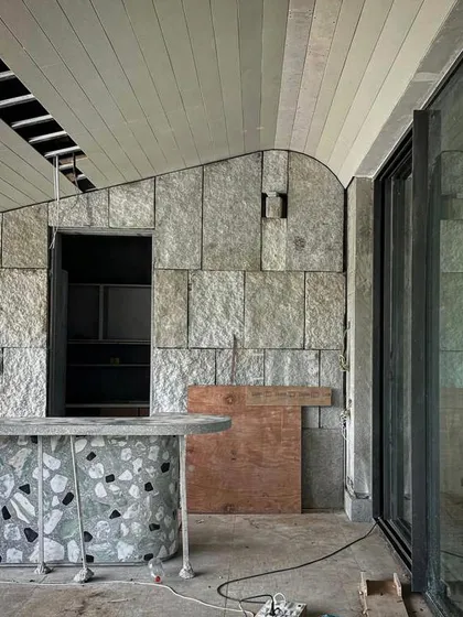 Progress on an Alibaug home during the monsoon. The image shows the combination of a curved granite wall and a terrazzo-style counter, highlighting our exploration of different stone finishes.