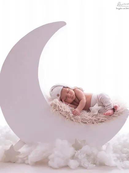 I love getting creative in my studio. Here, a sweet newborn dreams peacefully on a crescent moon prop, surrounded by soft clouds, creating a truly magical and whimsical portrait.