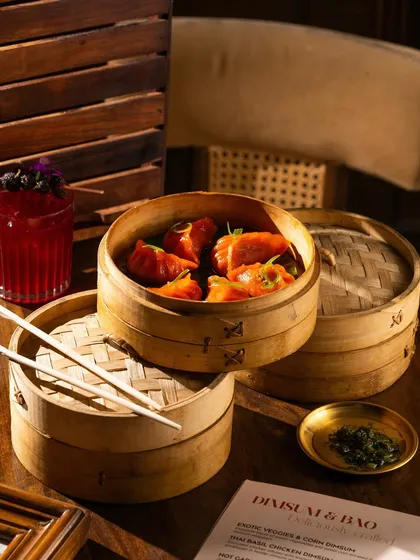 A stack of dim sum steamers in a cozy, warm setting. The lighting emphasizes the textures of the wood and the steam.