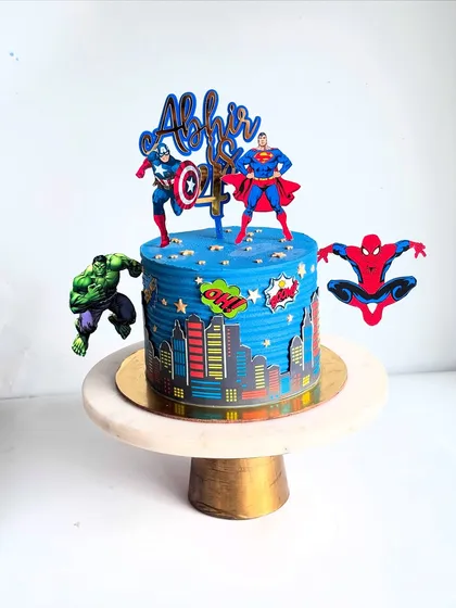 A still shot of the action-packed superhero cityscape cake. The vibrant blue ganache and comic-style details make it a perfect centerpiece for a young hero's birthday party.