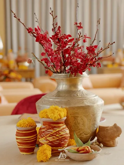 A beautiful centerpiece combining traditional brass vases, terracotta pots with marigolds, and vibrant red orchids for a pop of color.