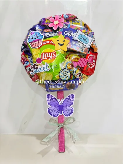 A close up of one of my giant lollipop hampers, bursting with a fun assortment of snacks like Lays, Kinder Joy, and various candies. These are always a huge hit at birthday parties and can be customized to include your child's favorite treats.
