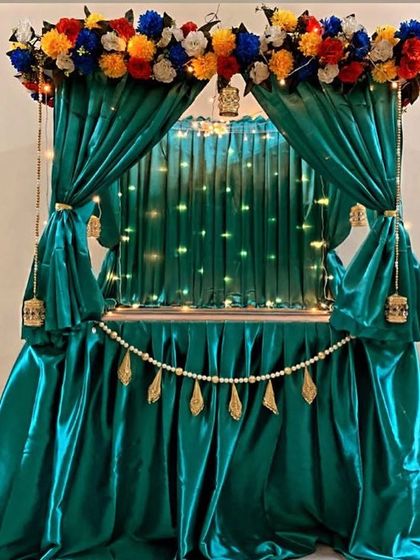 A rich, emerald green satin mandap with a border of colorful flowers. The pearl string and golden tassels add a touch of royalty to this unique design.