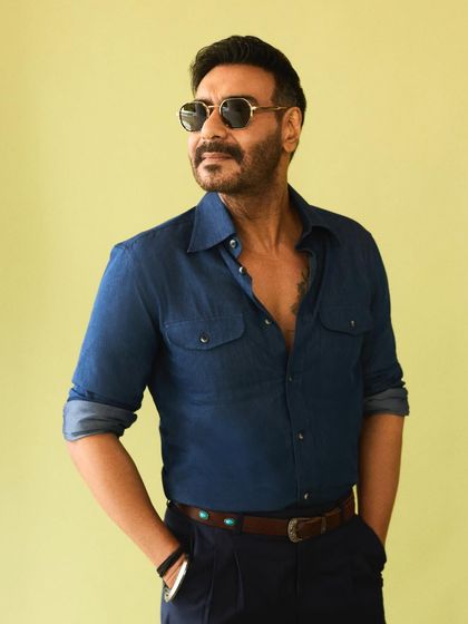 Ajay Devgn in a classic denim-on-denim look, styled with a relaxed open collar and cool sunglasses for a promotional event.