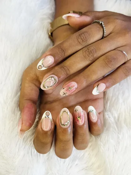 A chic and artistic set featuring a mix of techniques. It combines a marbled pink accent nail with others that have delicate gold chrome frames and starbursts.