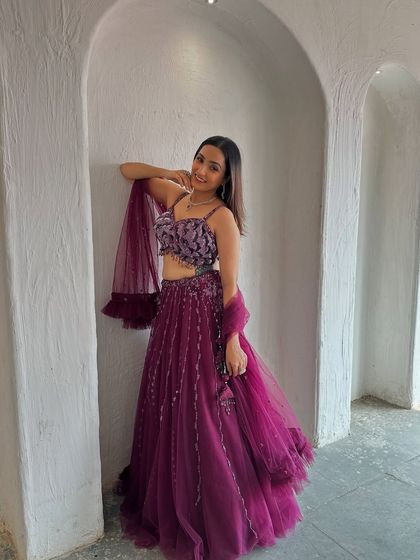 A relaxed and stylish pose in this beautiful wine-colored lehenga. It's a versatile piece that can be dressed up or down for any occasion.
