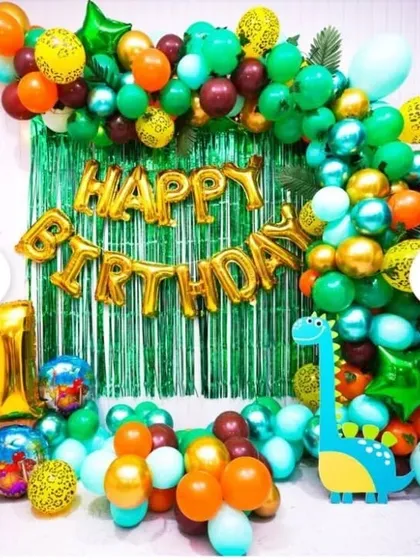 A dinosaur-themed birthday decoration for a home party, featuring a green shimmer curtain and a '1' foil balloon.