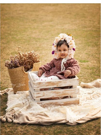 A dreamy outdoor first birthday shoot in a beautiful Gurugram park. This little one, snug in a rustic crate with a floral bonnet, looks like she's straight out of a storybook.