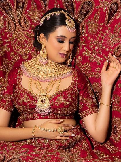 A look full of magic. This bride is surrounded by her magnificent red lehenga, with her makeup featuring a perfect base, subtle cheeks, and shimmery eyes.