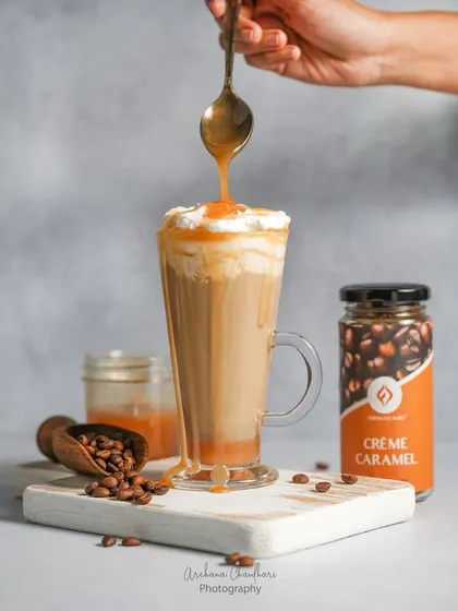 An action shot of a caramel coffee drink, freezing the moment the caramel is drizzled on top. This dynamic food photography makes the beverage look incredibly tempting and delicious.