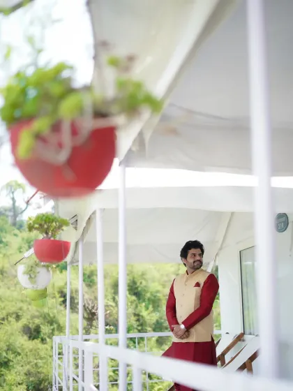 A relaxed groom's portrait on the balcony of a destination venue. The candid, over-the-shoulder shot feels natural and unstaged.