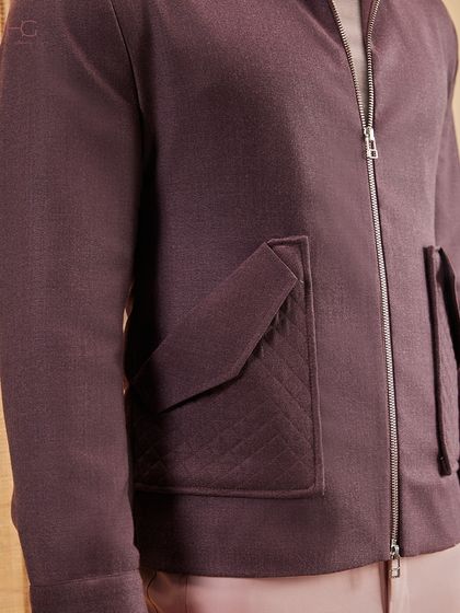 A close-up on the quilted pocket detail of this maroon zip-up jacket. It’s a subtle touch that adds texture and elevates the piece beyond the basics.