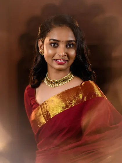 A simple and elegant portrait of a model in a maroon saree with a gold border. The soft, hazy lighting gives this 'Kanmani' inspired shot a dreamy and timeless feel.