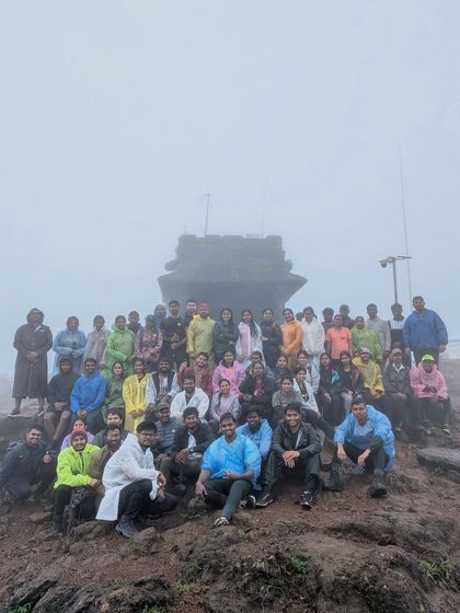 Our group posing in front of the Sarvajna Peetha at the Kodachadri summit, shrouded in mist.