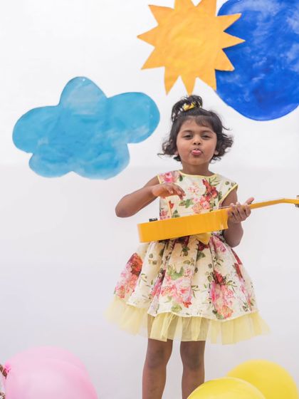 Another angle of the sunny floral party dress. The playful pose with the ukulele shows that this dress is perfect for a girl with a creative and fun-loving spirit.