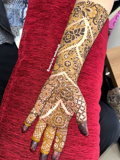 A designer mehendi with a unique, modern twist. The pattern uses negative space to create a beautiful vine-like effect.