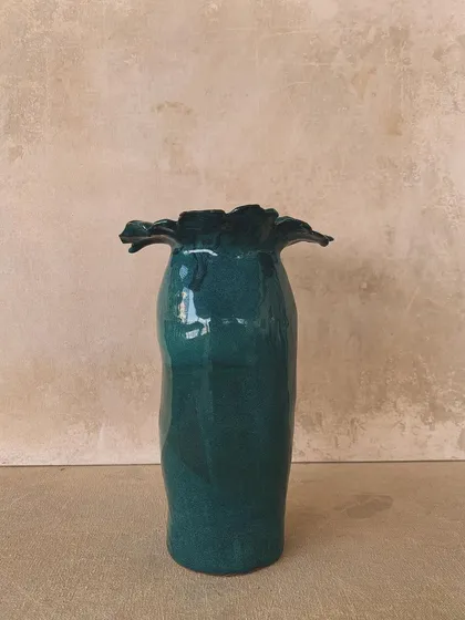 A tall, elegant vase with a ruffled top, glazed in a deep, rich teal. A statement piece for any room.