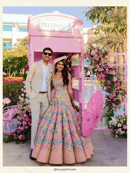The couple poses in front of a pink telephone booth adorned with flowers, a perfect, quirky photo opportunity that captures the fun spirit of the Victorian luncheon.
