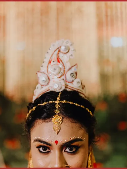 A striking close-up of the Bengali bride, focusing on her traditional 'mukut' and powerful eyes.