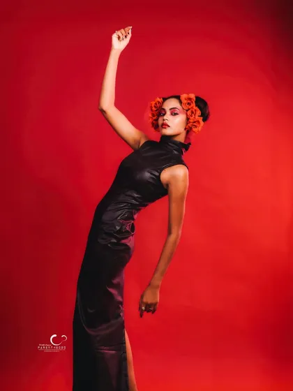 A graceful, elongated pose that highlights the sleek silhouette of the dress. The upward reach adds a sense of aspiration and artistry.