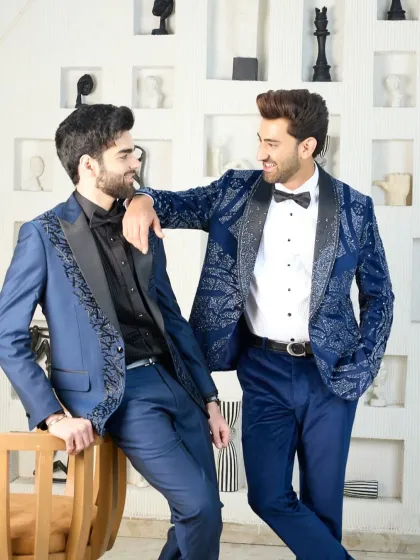 Double the style, double the sophistication. Two variations of my embellished blue tuxedos are shown here, one with intricate patterns across the jacket and the other with detailed lapels, perfect for a coordinated cocktail party look.
