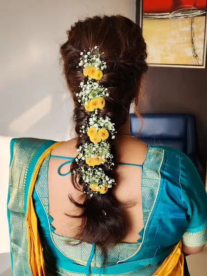 A beautiful mermaid braid adorned with fresh yellow flowers and baby's breath, perfect for a Haldi or daytime wedding ceremony.