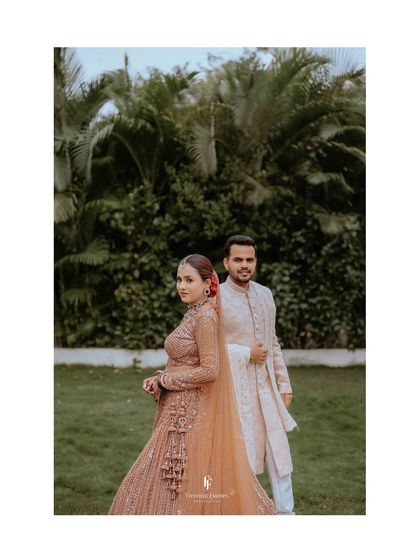 A stylish portrait of the couple standing in a lush green lawn, their elegant outfits contrasting beautifully with the natural setting.