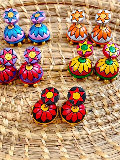 A duplicate image of the two-tiered floral jhumkas, laid out on a woven mat.