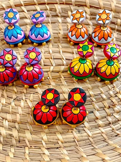 A duplicate image of the two-tiered floral jhumkas, laid out on a woven mat.