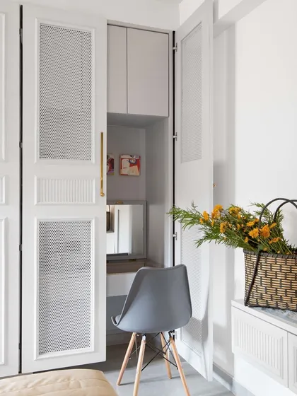 Functionality is hidden in plain sight. This elegant wardrobe features pocket doors that open and slide back to reveal a compact, fully functional study nook, complete with a desk and shelving. It is a perfect solution for maximizing space in a bedroom.