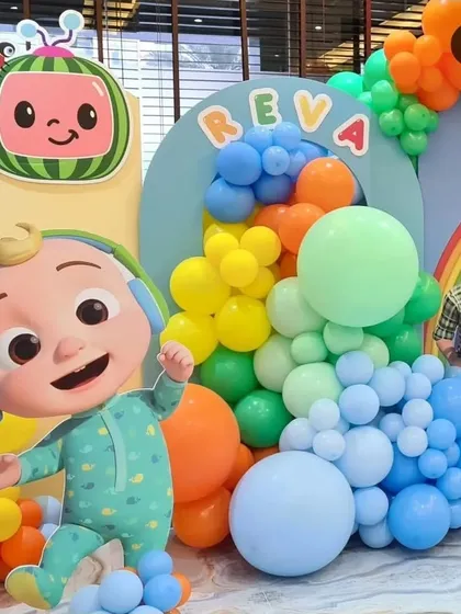 A close-up view of the Cocomelon party setup, highlighting the large JJ cutout and the vibrant, multi-colored balloon cascade that brings the theme to life.
