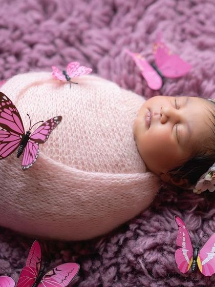 Another angle of our butterfly-themed newborn shoot, showing the baby peacefully asleep on a plush purple blanket.