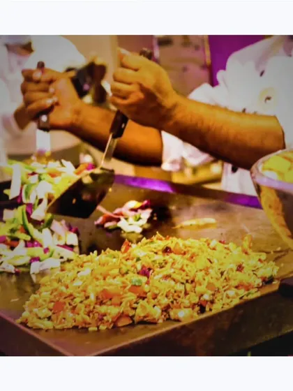 A chef at a live teppanyaki-style station, tossing a mix of rice and fresh vegetables on a large griddle. It's a dynamic and engaging food experience.