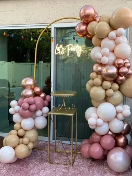 A "Let's Party" neon sign with a beautiful balloon arrangement in blush and rose gold. This setup is perfect for creating a fun and stylish photo corner at any celebration.