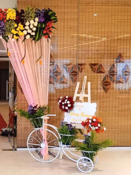 First impressions matter. I set up this beautiful entrance decor featuring a floral arrangement over the doorway, a welcome easel, and a decorative white bicycle with flower baskets to greet guests as they arrive.