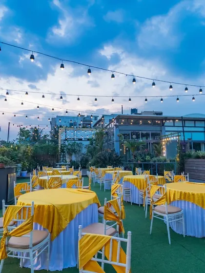 A daytime dining setup on our terrace, with yellow-themed tables under a blue sky, perfect for a lunch event or Mehendi ceremony.